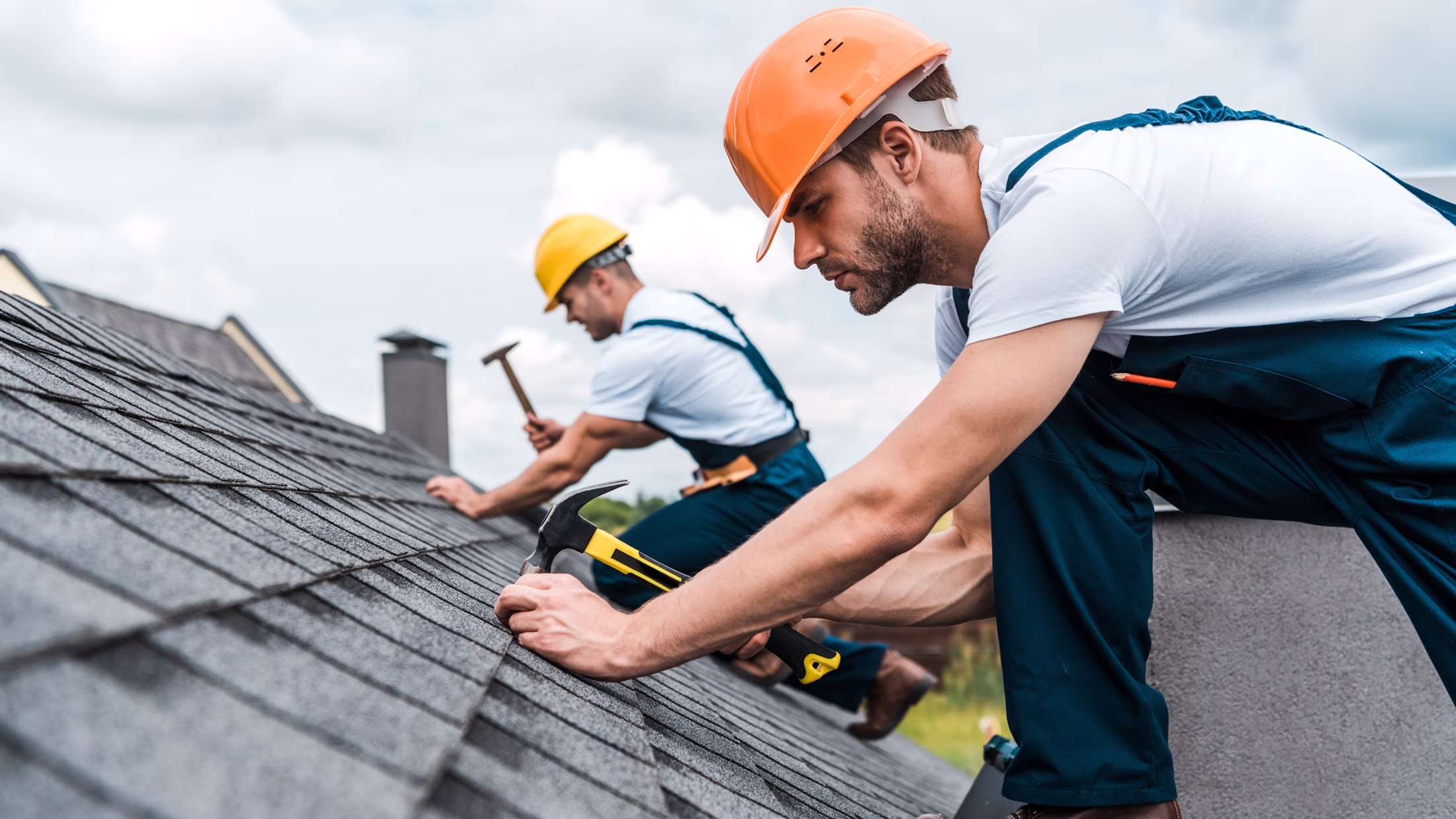 Dachdecker bei der Arbeit auf einem Steildach mit Bitumenschindeln