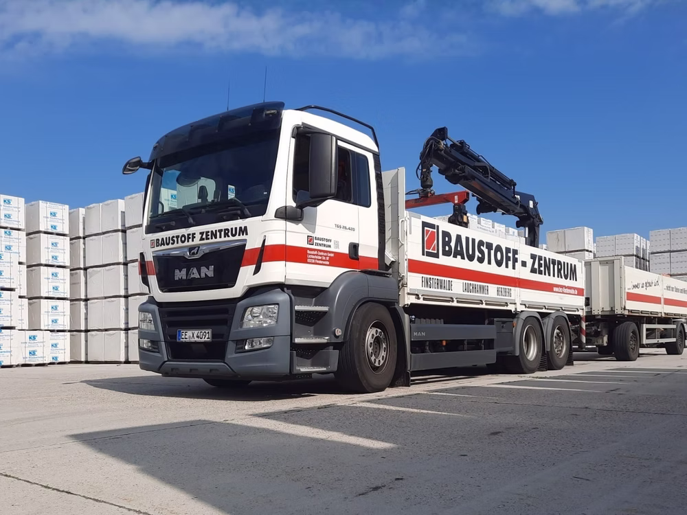 Firmen-LKW mit Ladekran vor der Baustoffhalle